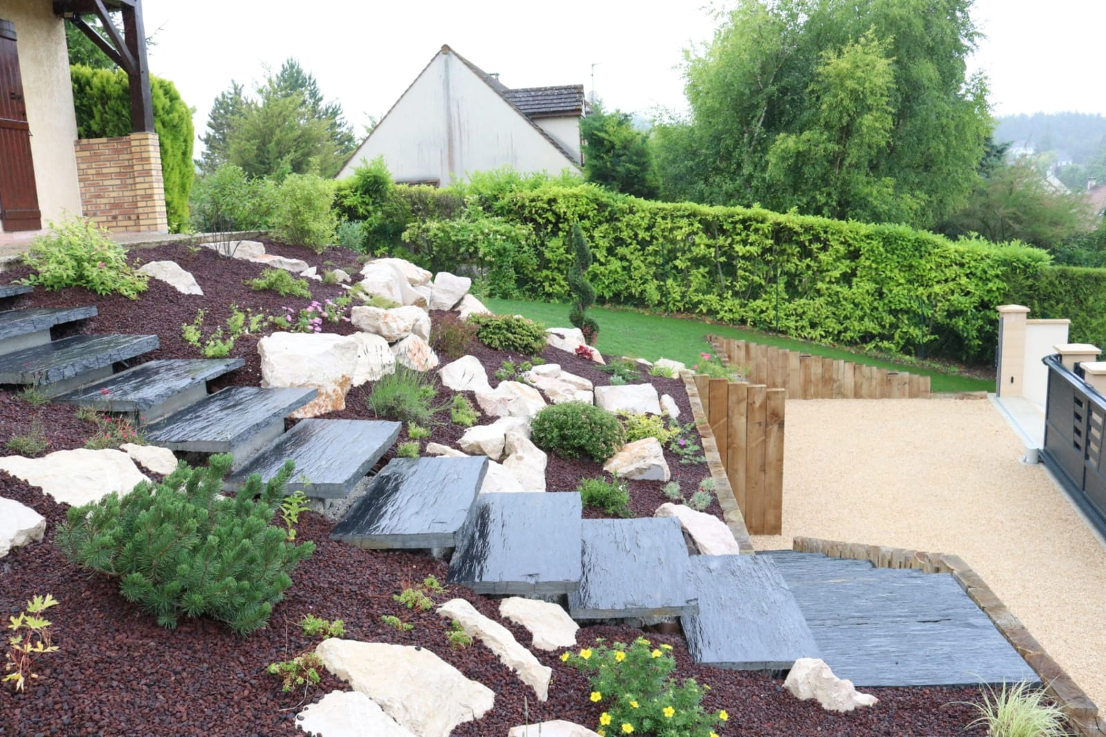 Aménagement paysager avec des escaliers en pierres et des plantes variées, création d'un jardin esthétique et fonctionnel par RC Espaces Verts.